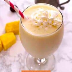 a pineapple smoothie topped with whipped cream with a red straw.