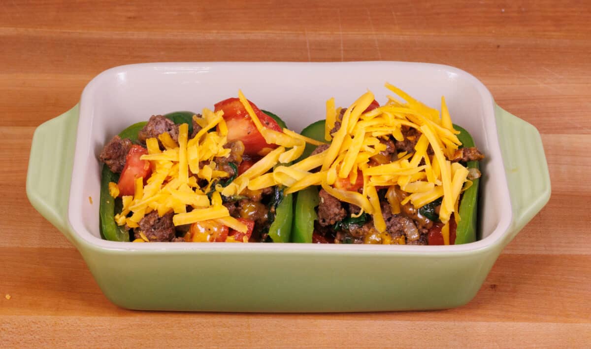 two stuffed peppers in a green baking dish