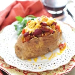 a baked potato stuffed with beans and cheese and chili on a white plate