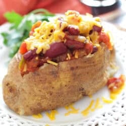 a baked potato topped with chili on a white plate.