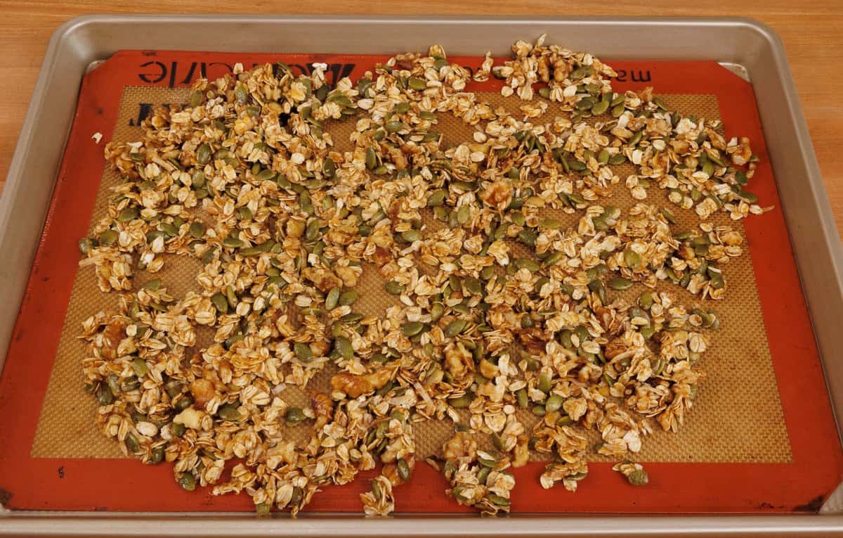 spreading pumpkin granola out over a large baking pan