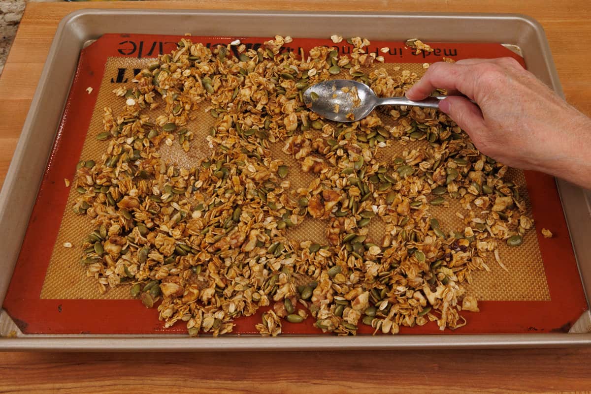 stirring granola before baking on a baking sheet