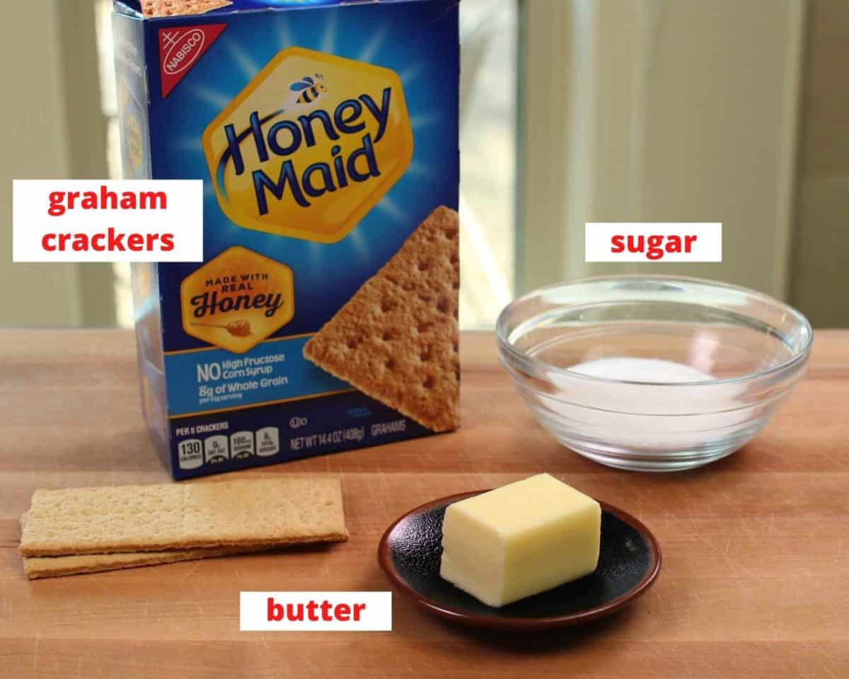 graham crackers, butter and sugar on a brown table.
