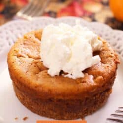 a single serve pumpkin pie on a white plate topped with whipped cream.