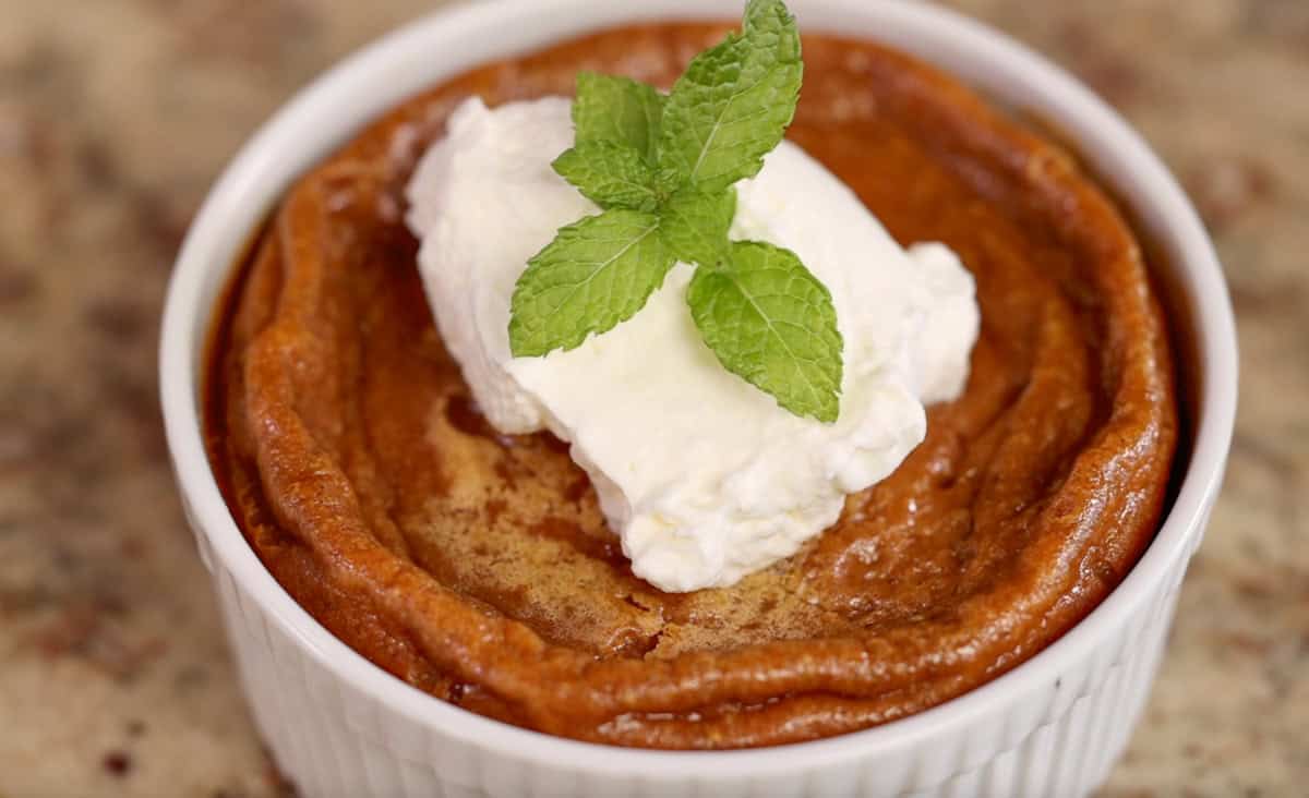 a small pumpkin pie in a ramekin topped with whipped cream and fresh mint.