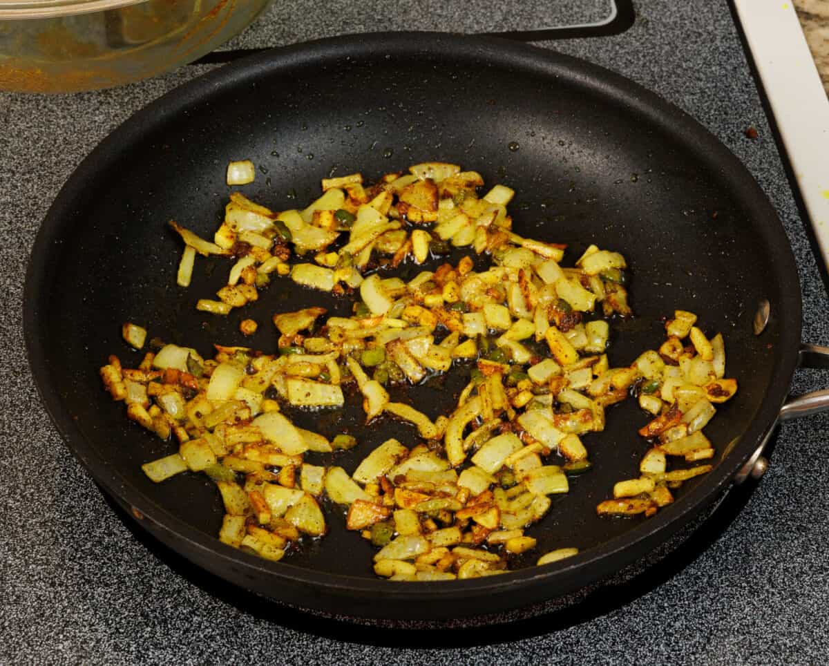 onions, garlic, ginger, and peppers cooking in a pan