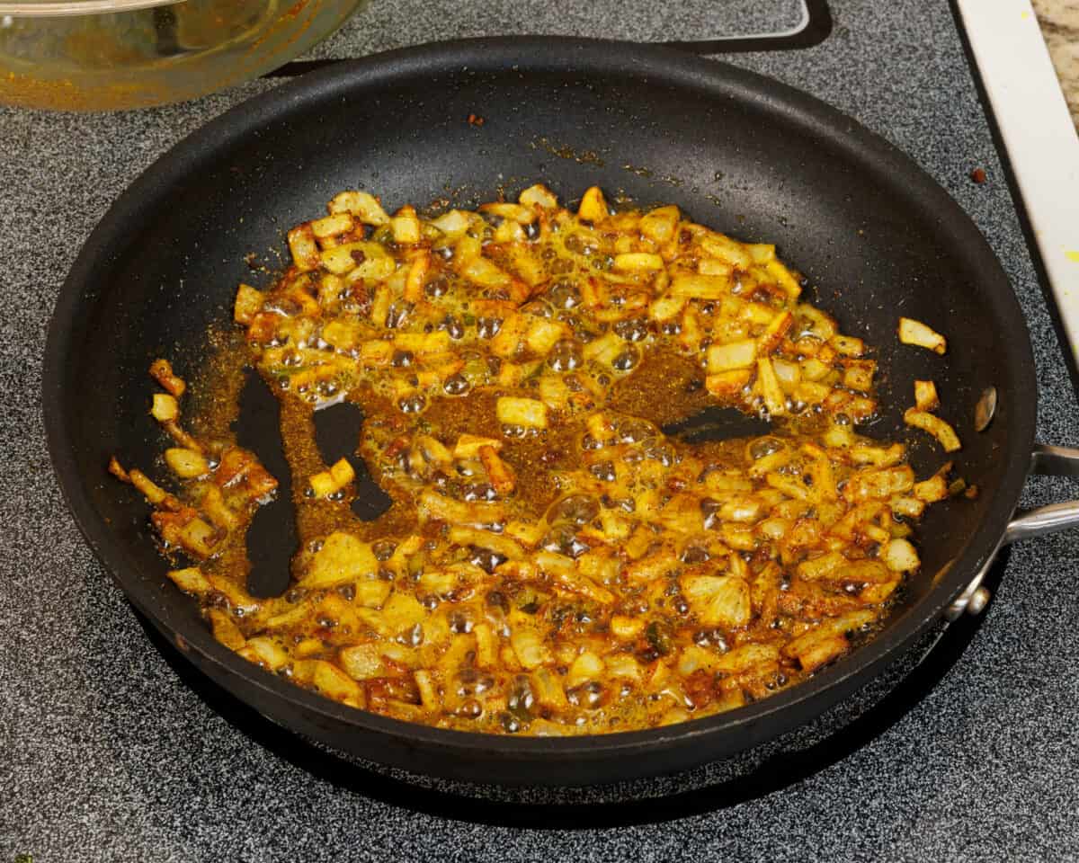 vegetables cooking in butter in a small black skillet