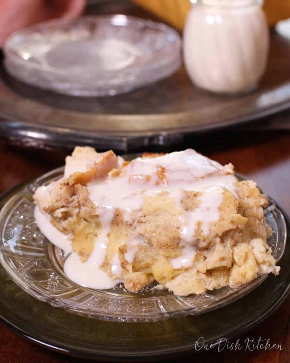 bread pudding topped with whiskey sauce on a plate next to a jar of whiskey sauce.