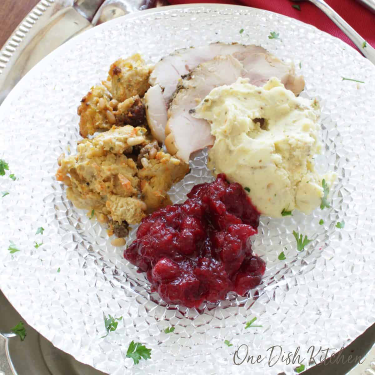 a plate filled with stuffing, turkey, cranberry sauce and mashed potatoes.