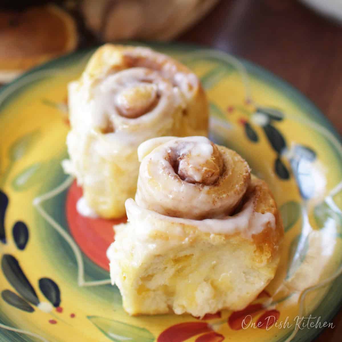 two mini glazed cinnamon rolls on a plate.