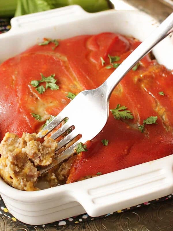 a small bacon cheeseburger meatloaf topped with a ketchup and mustard glaze in a small white baking dish.