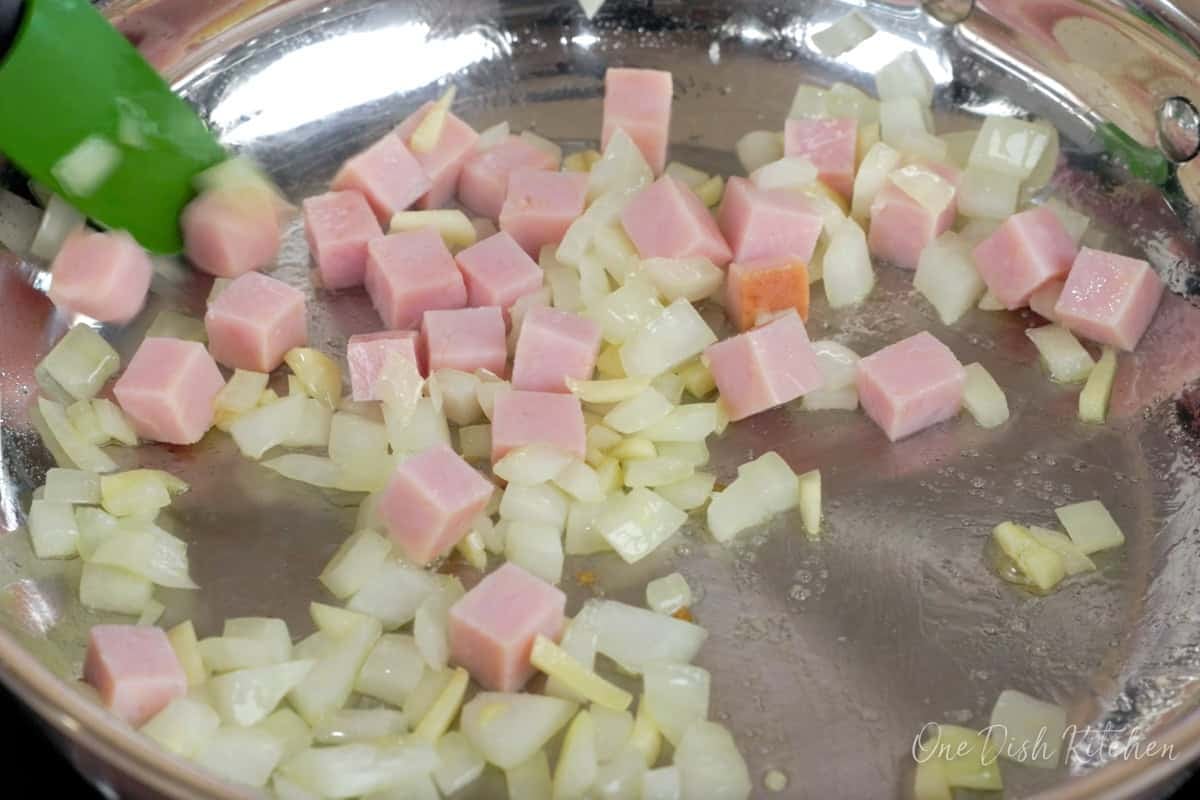 diced ham in a skillet heating with onions and garlic.