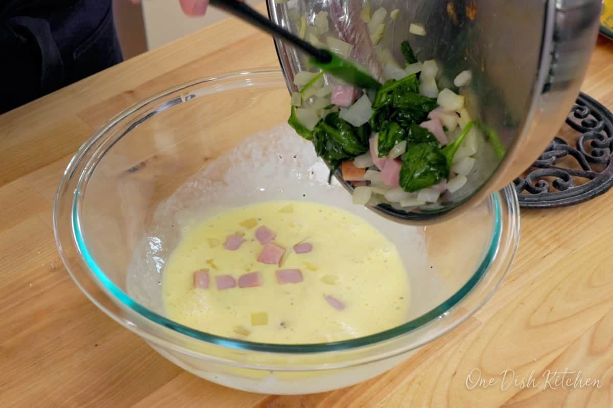 eggs, cream, spinach and ham in a mixing bowl.