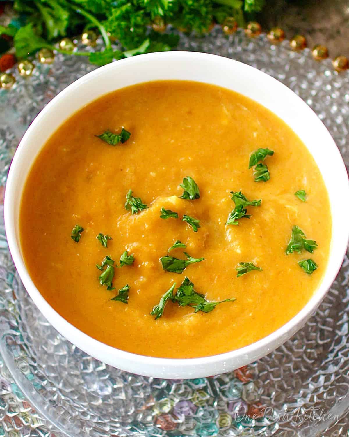 a small batch of curried butternut squash soup in a white bowl.