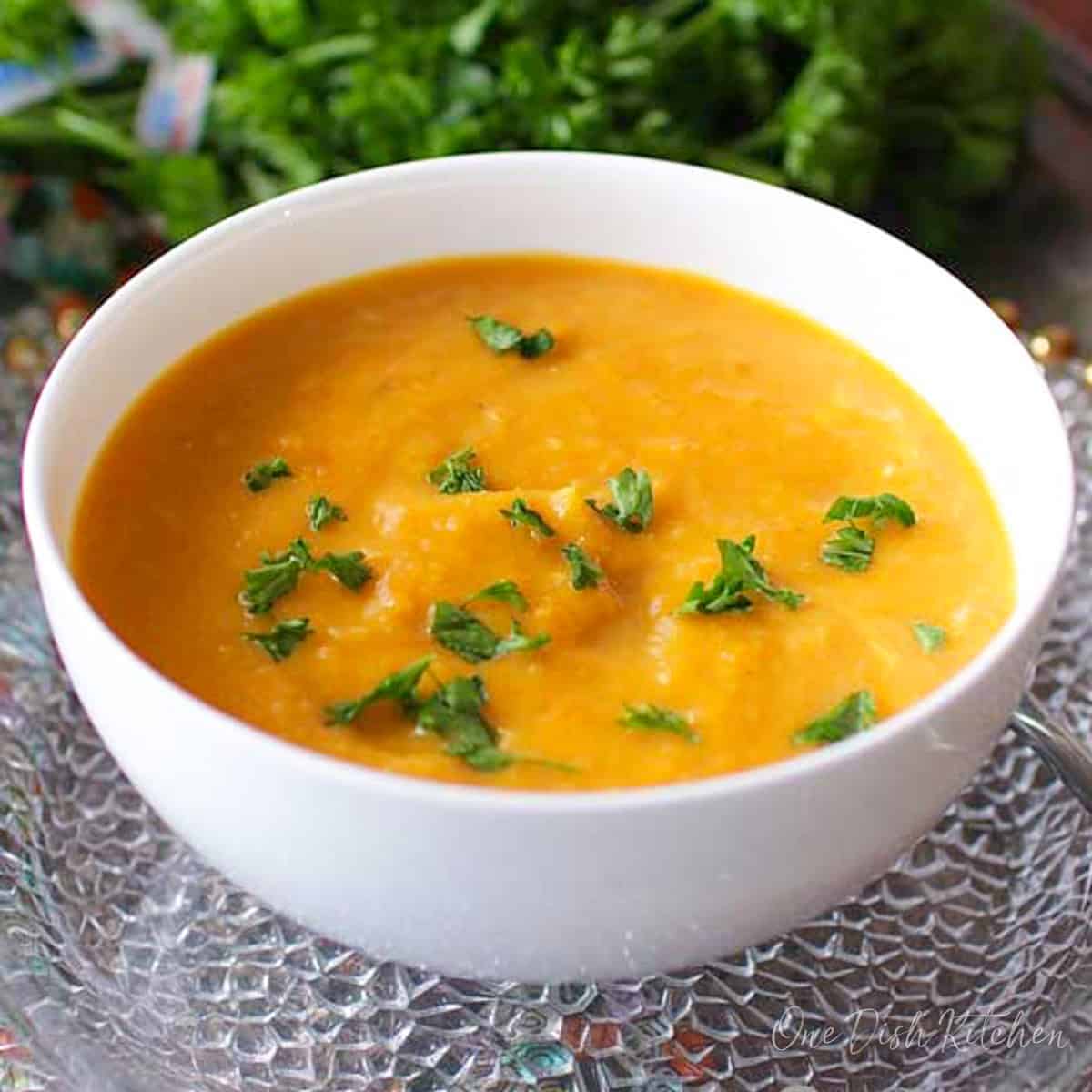 a single serving of butternut squash soup with curry in a white bowl.