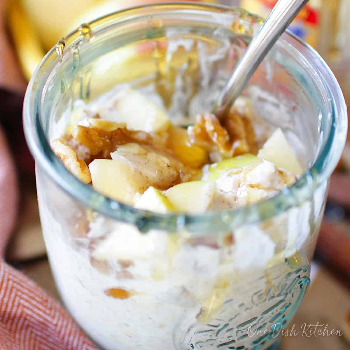 overnight oats in a jar topped with apples, walnuts, and honey.
