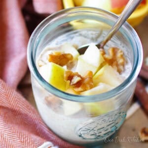 a jar of overnight oats with rolled oats, yogurt, milk, apples, nuts and honey.