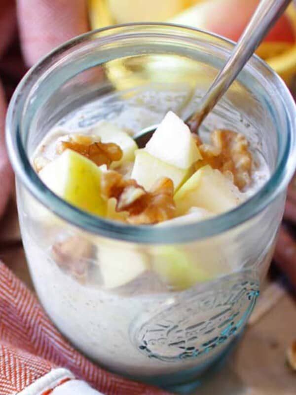 a bowl of overnight oats topped with apples and pecans