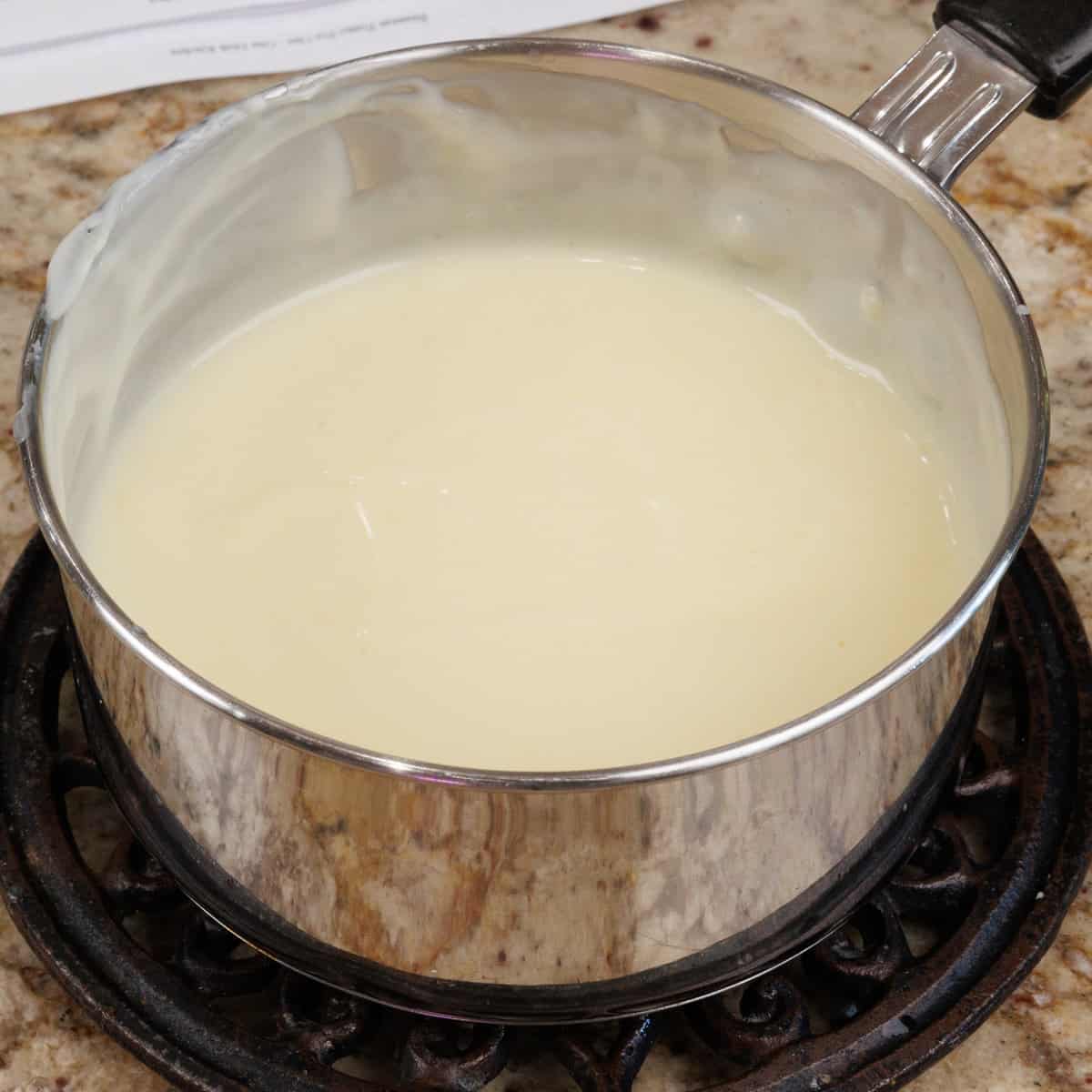 vanilla pudding in a small pot cooking on a kitchen counter