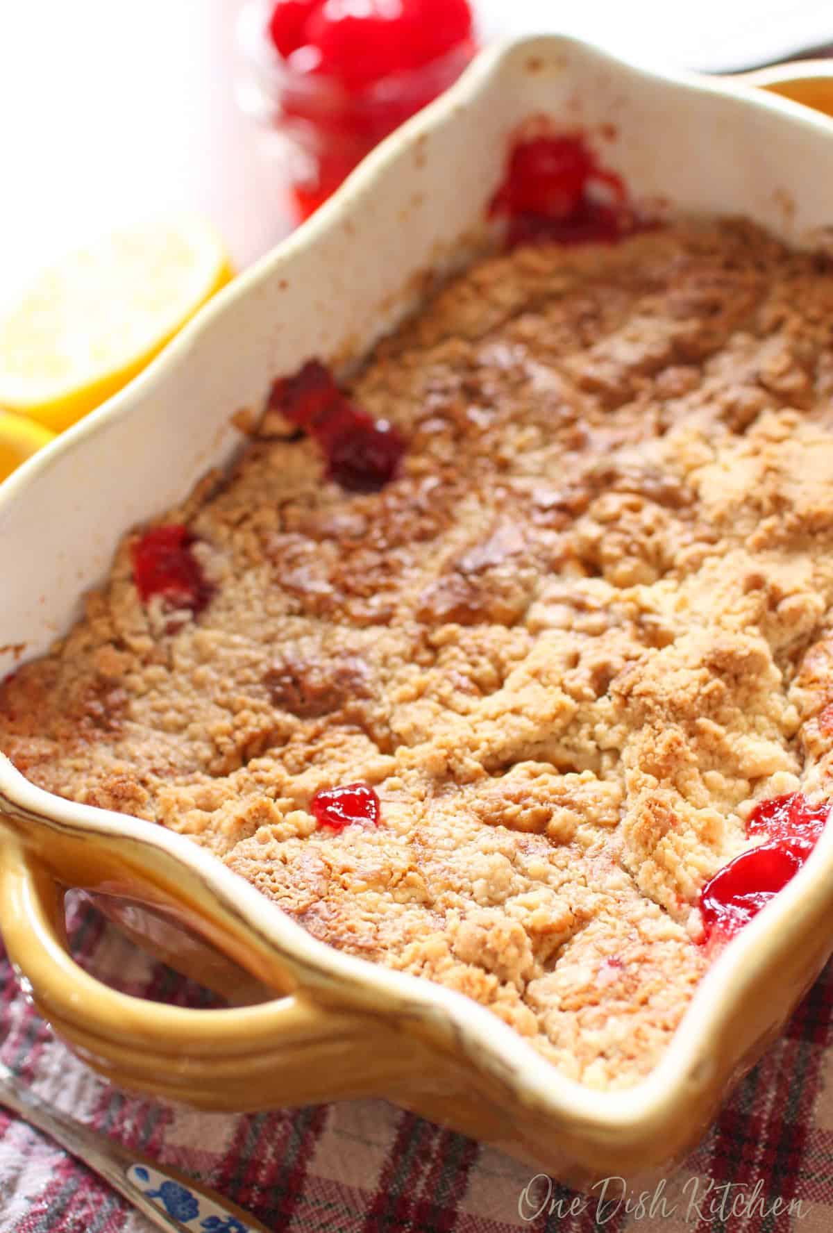 a mini cherry dump cake in a small baking dish made with canned pie filling and boxed cake mix.