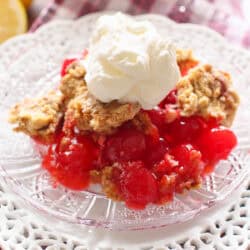 a single serving of cherry dump cake on a plate topped with whipped cream.