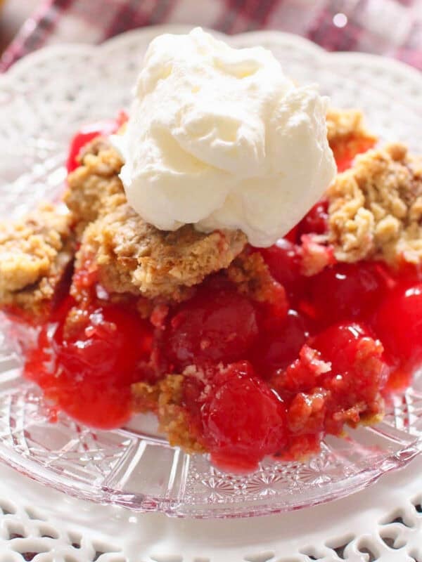 a single serving of cherry dump cake on a plate topped with whipped cream.