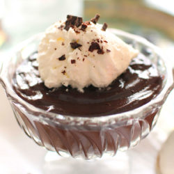 a small bowl of chocolate pudding topped with whipped cream and chocolate shavings.