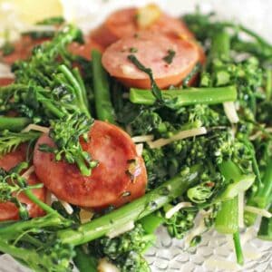 Sausage and Broccolini on a white dish.