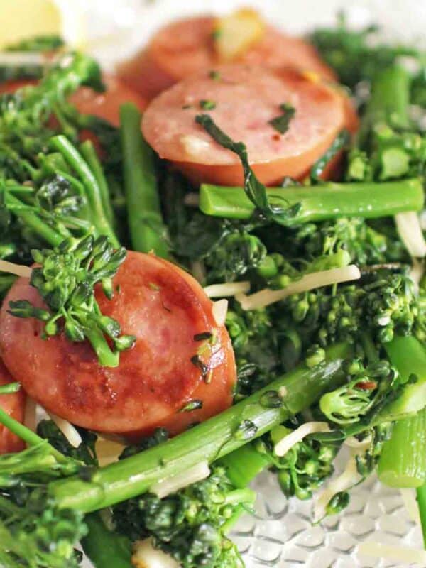 Sausage and Broccolini on a white dish.