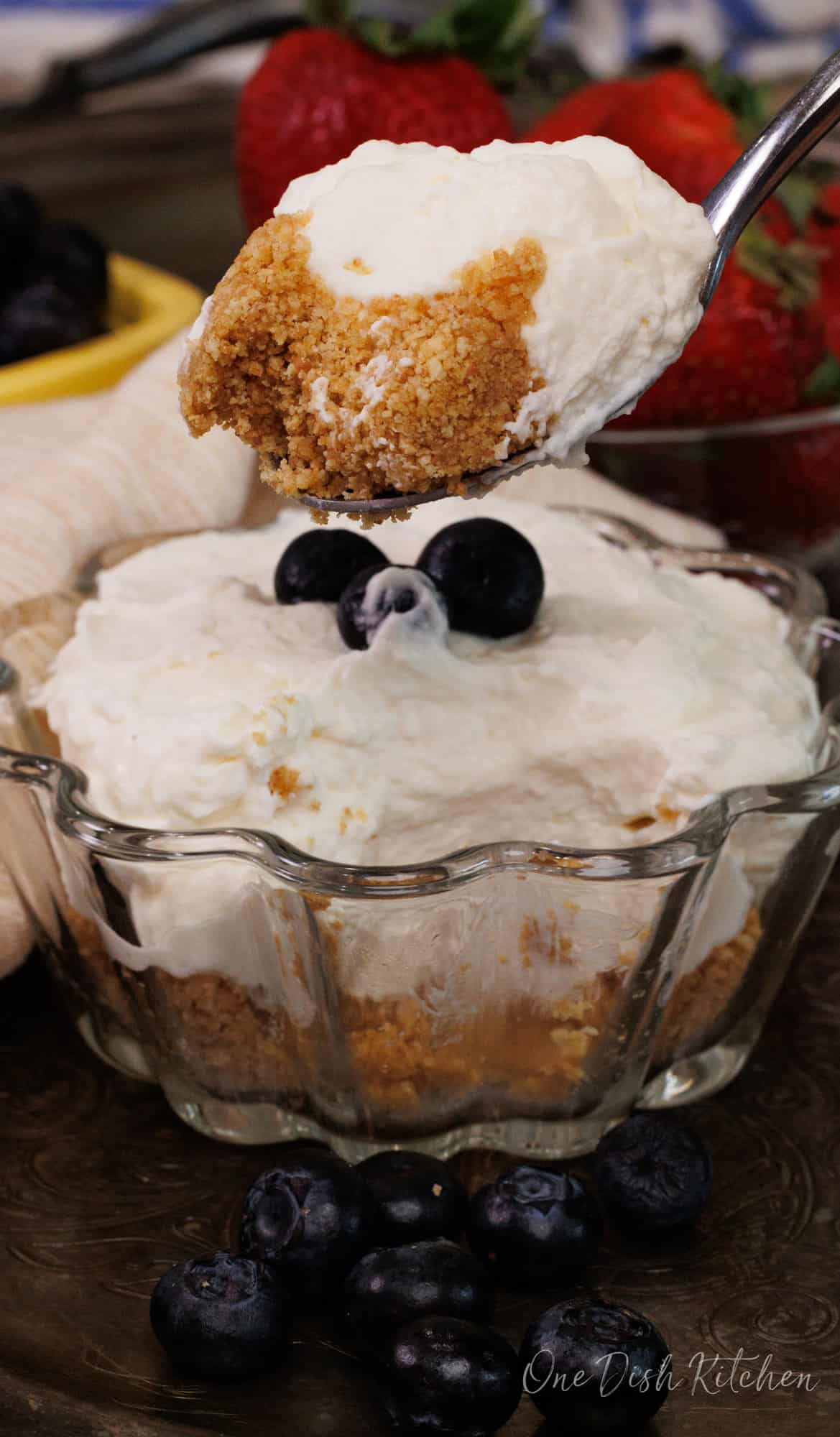 one small no bake cheesecake in a dessert dish with a spoon on the side