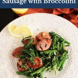 sauteed broccolini tossed with slices of smoked sausage on a white plate.