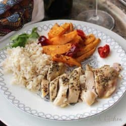 sheet pan chicken cut up with rice and carrot slices on white plate