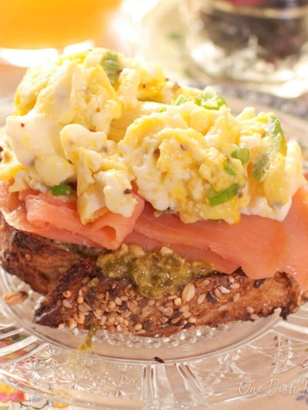 smoked salmon with scrambled eggs and pesto on a slice of bread.