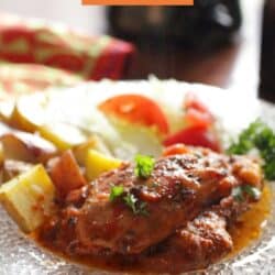 Italian chicken on a white plate next to roasted potatoes.