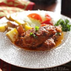 chicken thighs topped with marinara sauce next to roasted potatoes on a clear plate