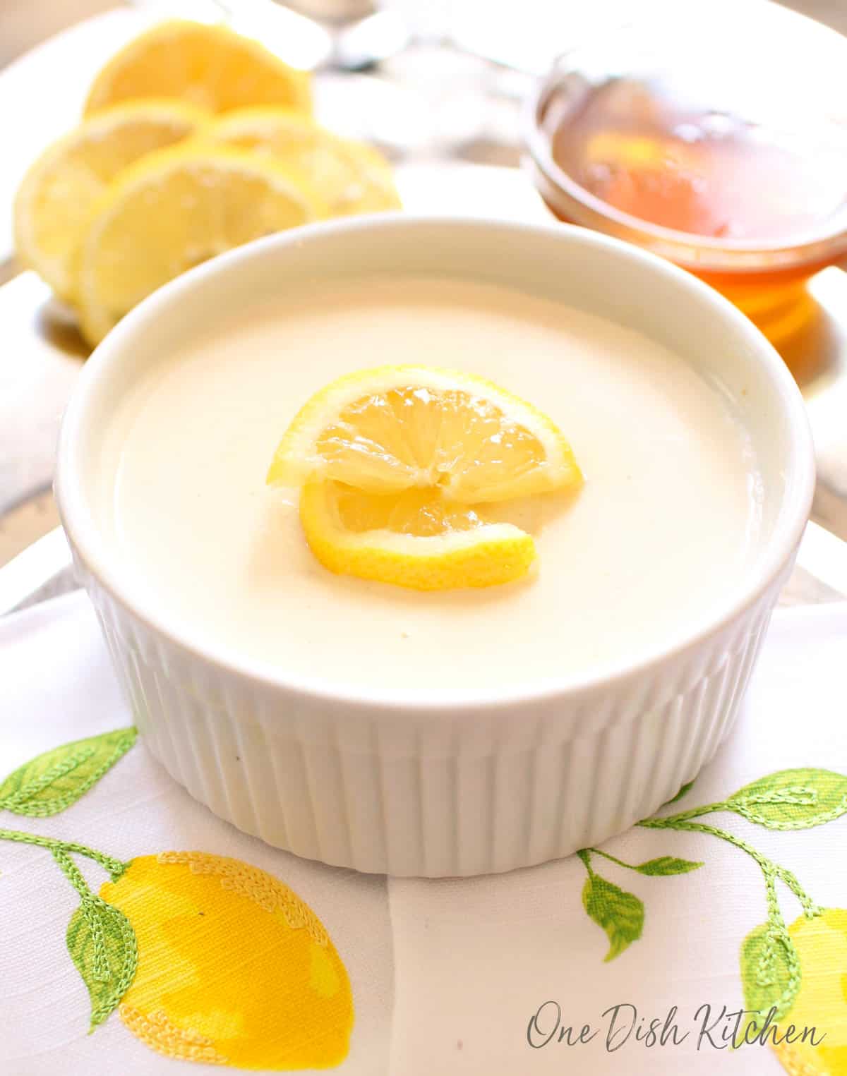 one lemon posset in a white ramekin topped with lemon slices.