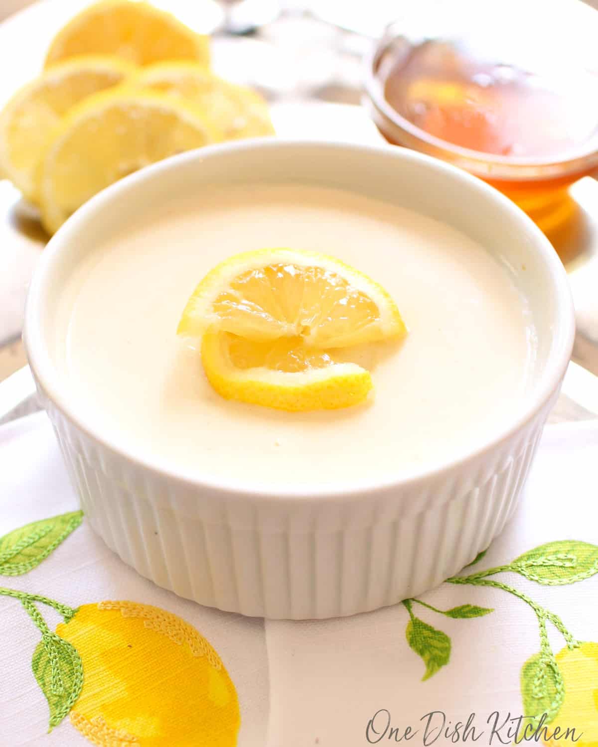 one lemon posset in a white ramekin topped with lemon slices.