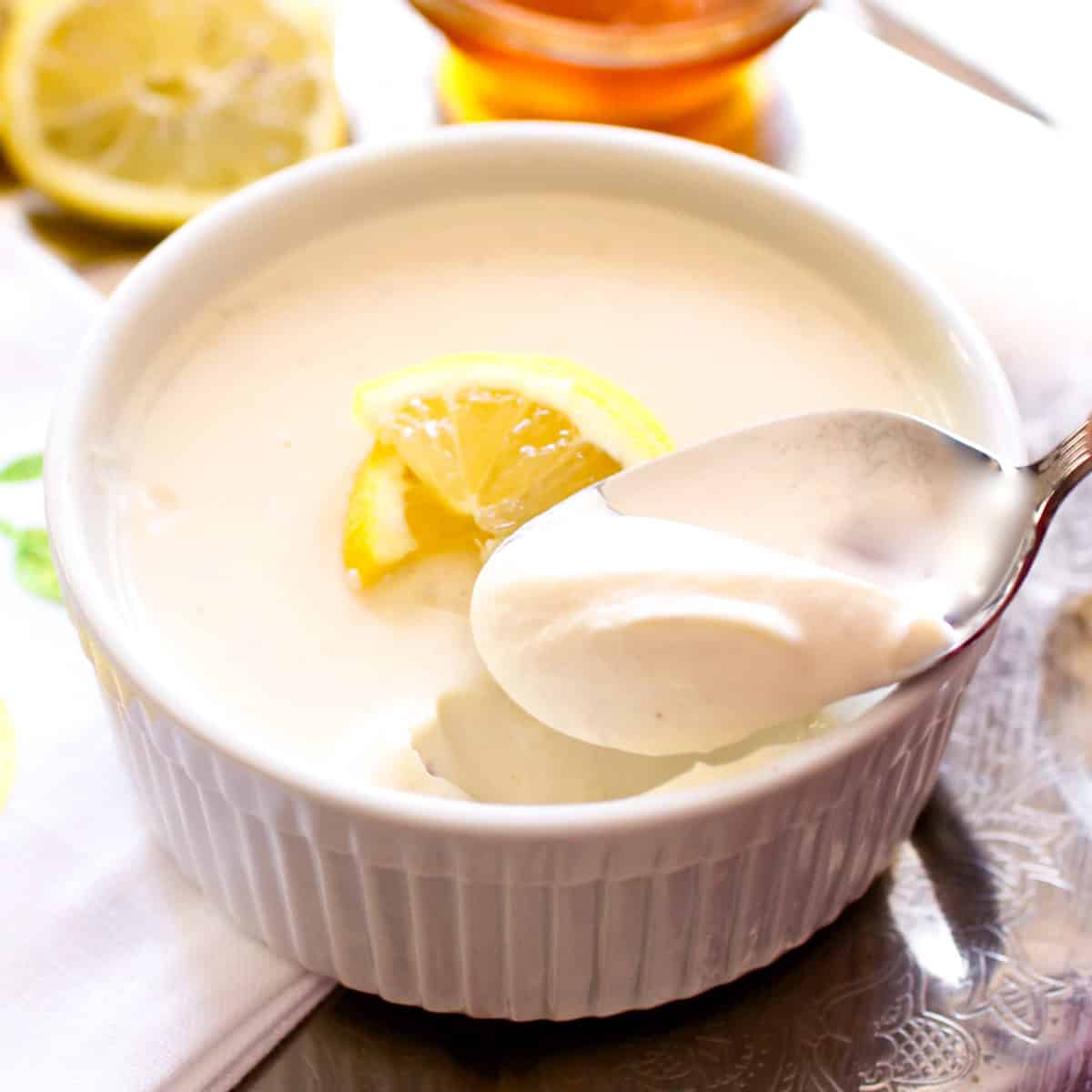 a lemon posset with a spoon on the side of the ramekin.