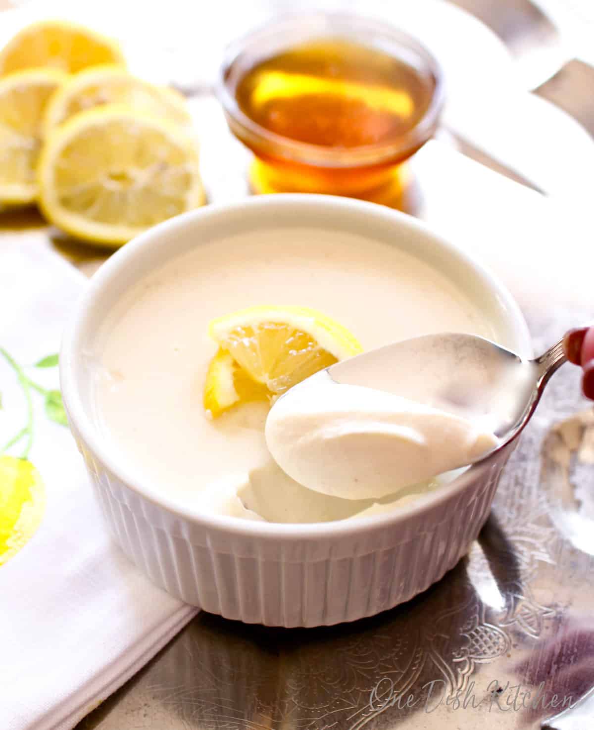 a lemon posset with a spoon on the side of the ramekin.