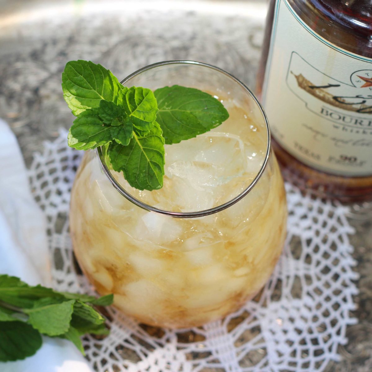 an overhead view of a mint julep in a clear glass with a sprig of mint floating on the top