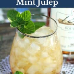 a mint julep with fresh mint next to a bottle of bourbon.