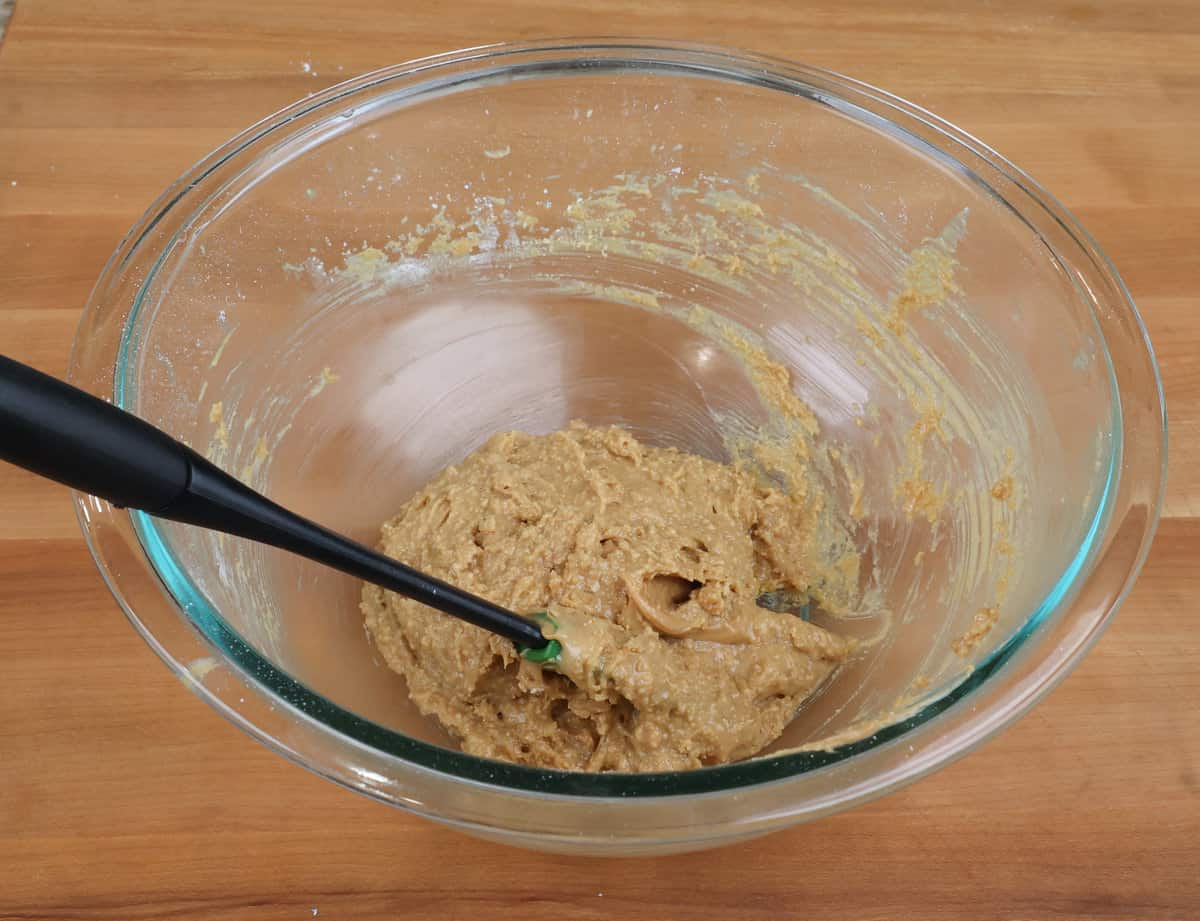 peanut butter bars batter in a mixing bowl with a rubber spatula on the side.
