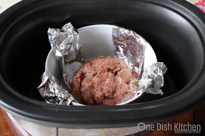 Cooking a meatloaf in a small bowl placed inside a large slow cooker.