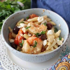 bowl filled with shrimp, pasta, vegetables, and feta.