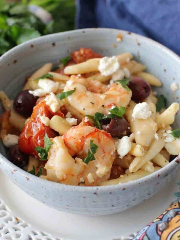 bowl filled with shrimp, pasta, vegetables, and feta.