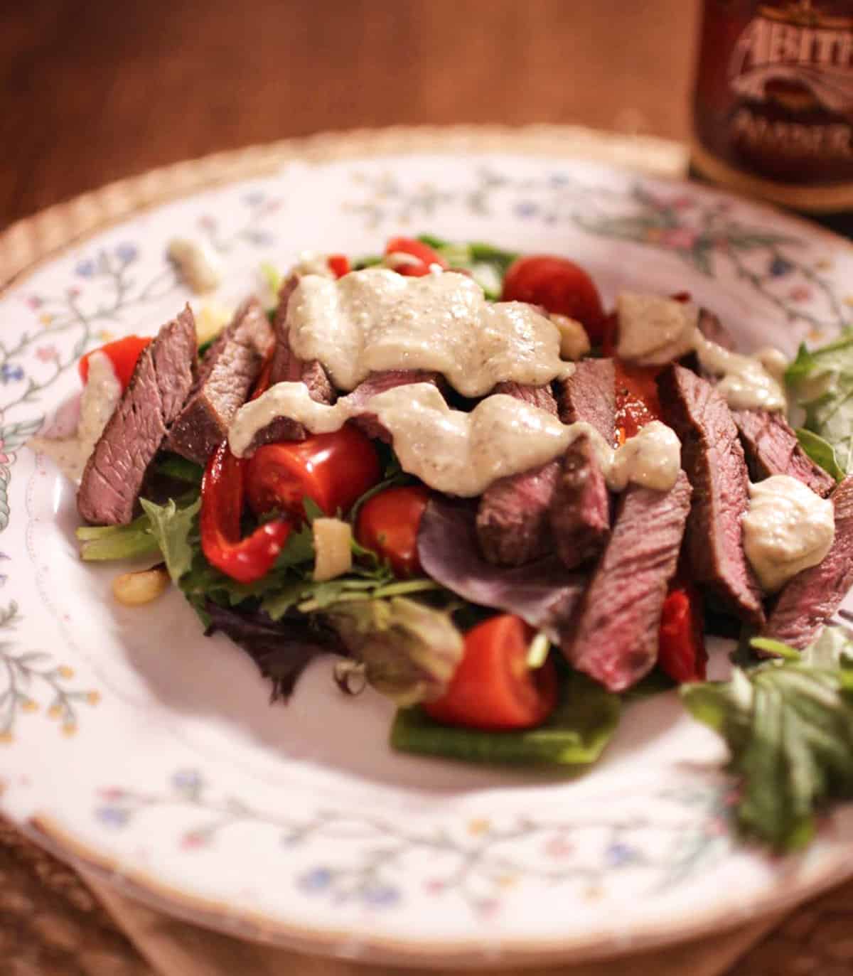 a steak salad topped with gorgonzola dressing.