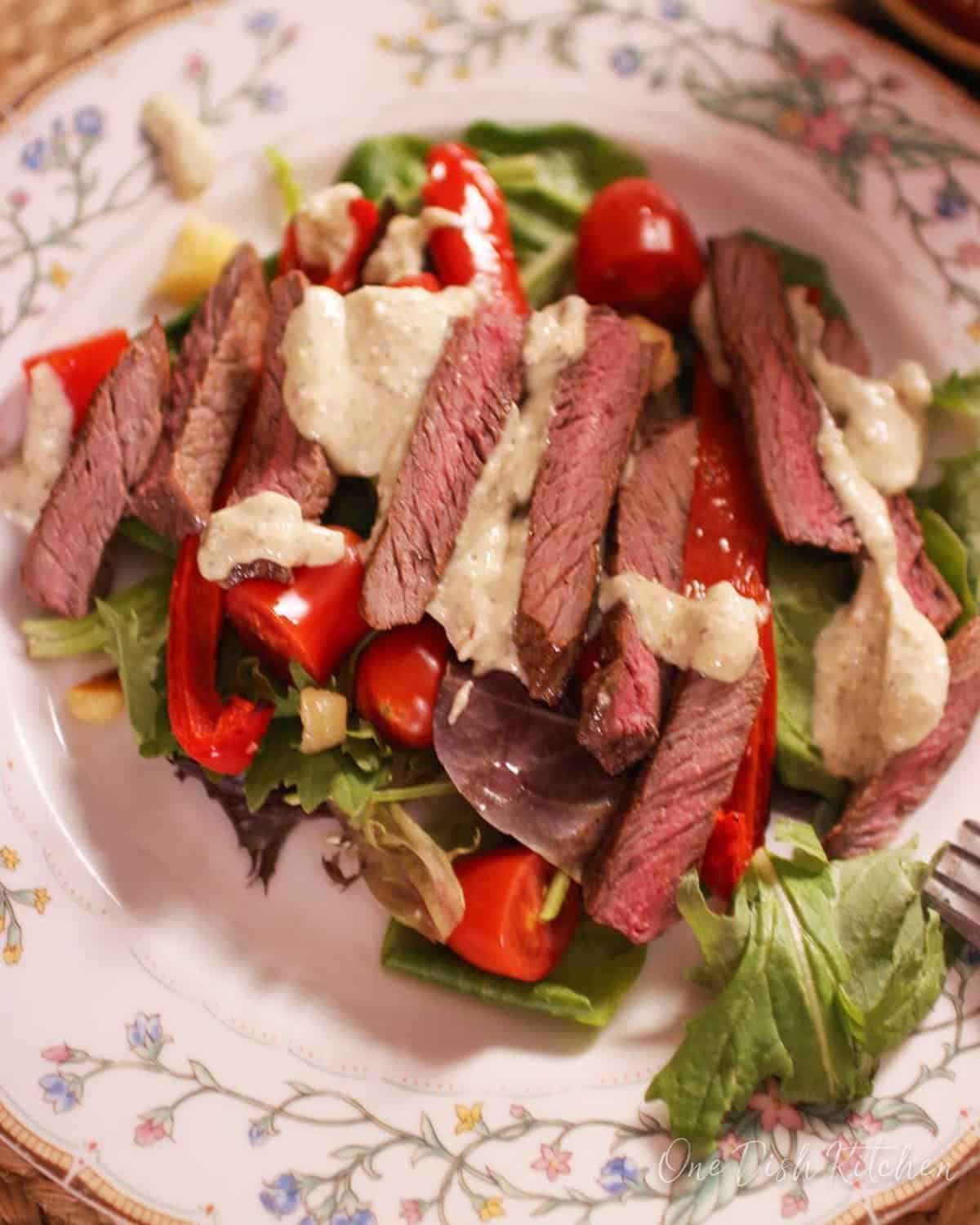 a steak salad topped with gorgonzola dressing.