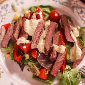 a steak salad topped with gorgonzola dressing.