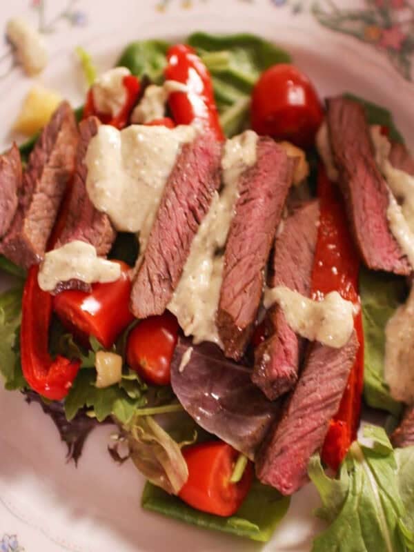 a steak salad topped with gorgonzola dressing.