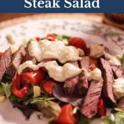 a steak salad on a plate topped with Gorgonzola dressing.